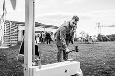 a man standing on top of a piece of equipment in the grass next to a building