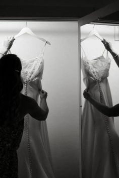 a woman is looking at her wedding dress in the mirror