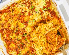 a casserole dish with spaghetti and meat in it on a plate next to a fork