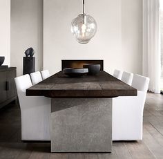 a dining room table with white chairs and a bowl on the center piece in front of it