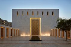 an empty building with columns and lights on the outside, in front of a tree