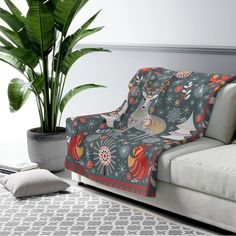 a living room with a couch, potted plant and decorative throw blanket on it