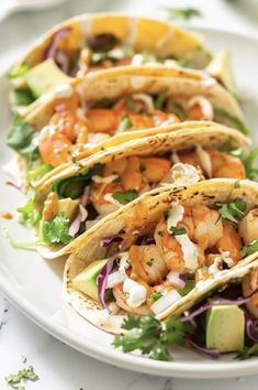 three shrimp tacos on a white plate