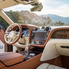 the interior of a car with dashboard, steering wheel and center console in front of mountains