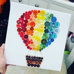 a person holding up a card with buttons in the shape of a hot air balloon