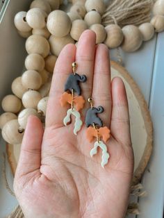 the small elephant earrings are on display in someone's hand next to some beads