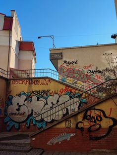 some graffiti on the side of a building with stairs leading up to it and buildings in the background