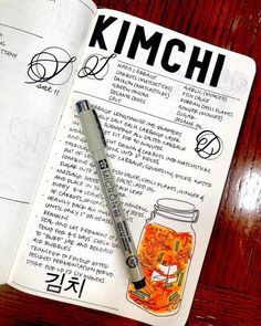 an open book with writing on it and a pen sitting next to it, in front of a wooden table