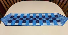 a table runner made out of blue and white squares on top of a dining room table