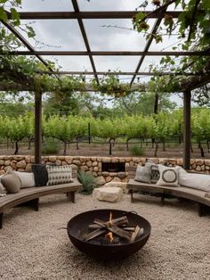 an outdoor seating area with couches, pillows and a fire pit in the middle