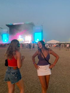 two women standing in the sand at a music festival