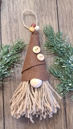 an ornament made out of yarn and buttons on a wooden surface with pine branches