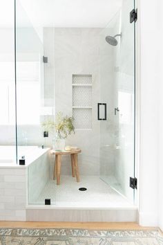 a white bathroom with a walk in shower next to a bathtub and sink area