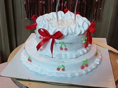 a white cake with red bows and candles on it sitting on top of a table