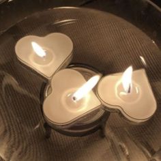 three heart shaped candles sitting on top of a glass plate in the shape of hearts