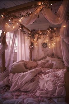 a canopy bed with lights hanging from it's sides and pillows on the bottom