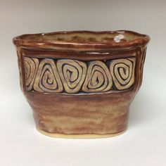 a brown ceramic bowl sitting on top of a white table