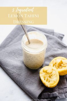 a glass jar filled with lemon tahiti dressing on top of a gray napkin next to sliced oranges