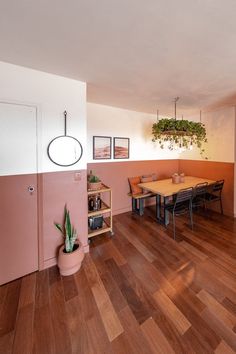 a dining room with wood flooring and pink walls, potted plants on the wall