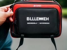 a person holding a black and red bag with the word billemhei on it