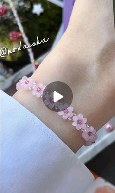 a woman wearing a bracelet with pink flowers on it