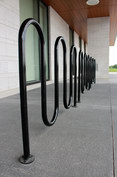 a row of black bike racks next to a building