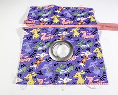 a purple and pink fabric with an animal pattern on it, next to a pair of scissors