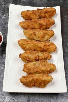 fried chicken strips are lined up on a white plate