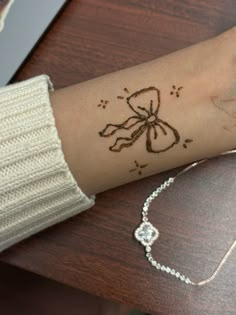 a woman's arm with a tattoo that has a bow on it and beads around the wrist