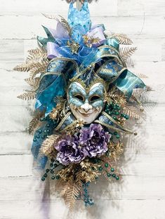 a mask hanging on the wall with blue and purple flowers in it's center