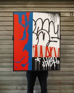 a man holding up a large piece of art with graffiti on it's sides