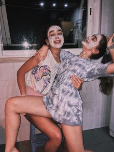 two girls with face paint on their faces are hugging each other in front of a window