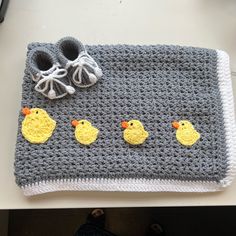 there is a crocheted baby blanket with ducks on it and two pairs of shoes