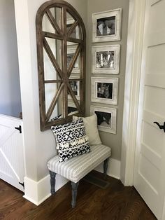 a white bench sitting next to a wall with pictures on it and a mirror above it