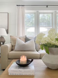 a living room with a couch, coffee table and vase filled with flowers on top of it