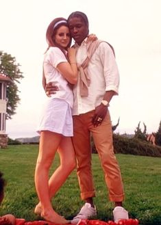 a man and woman standing next to each other in front of tomatoes on the ground