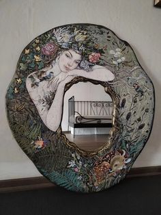 a mirror with a woman's face on it and flowers in the reflection, against a white wall