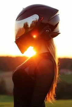 a woman wearing a helmet with the sun setting behind her