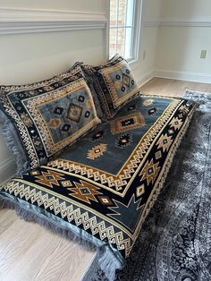 a bed with two pillows on top of it next to a large rug and window