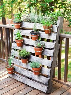 a wooden pallet filled with potted plants on top of a wooden deck next to trees