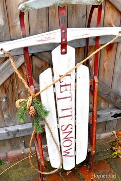 an old sled is decorated with pine cones and twine to hold the sign