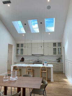 an open kitchen and dining room with skylights above the counter top, along with chairs