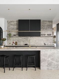 a kitchen with marble counter tops and black bar stools