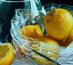 an oil painting of oranges in a glass bowl on a table with silverware