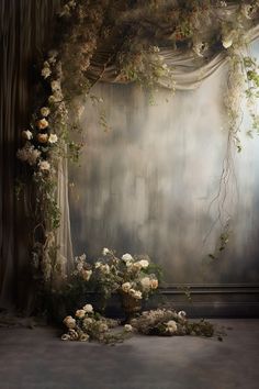 an arrangement of flowers and vines in front of a curtain