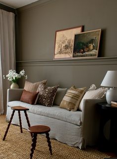 a living room with a white couch and some pictures on the wall above it's windows