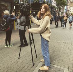 a woman is filming on the street with her camera