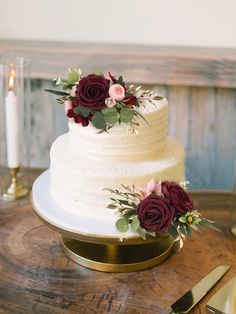 a wedding cake with flowers on it sitting on a table next to a knife and fork