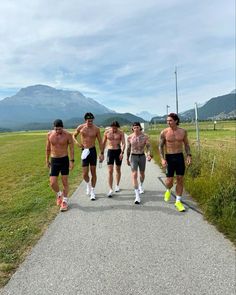 four shirtless men running down a road