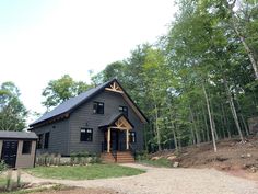 a house in the woods with trees and gravel path leading up to it's front door